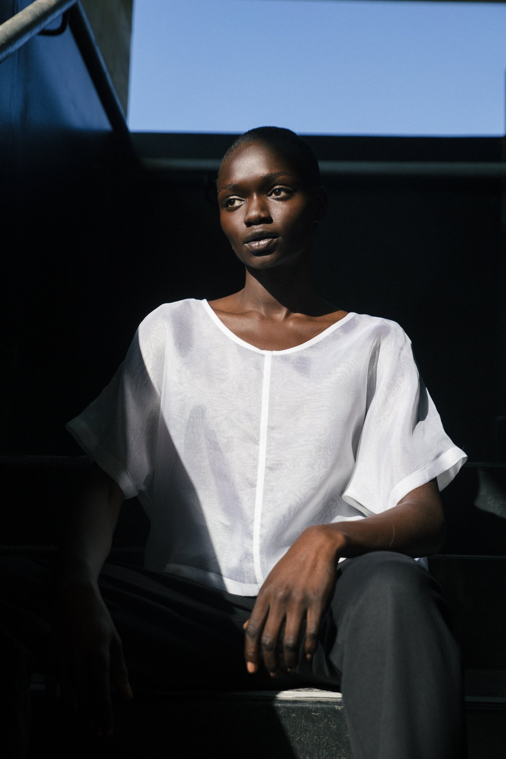 Person wearing a white shirt sitting against a dark background
